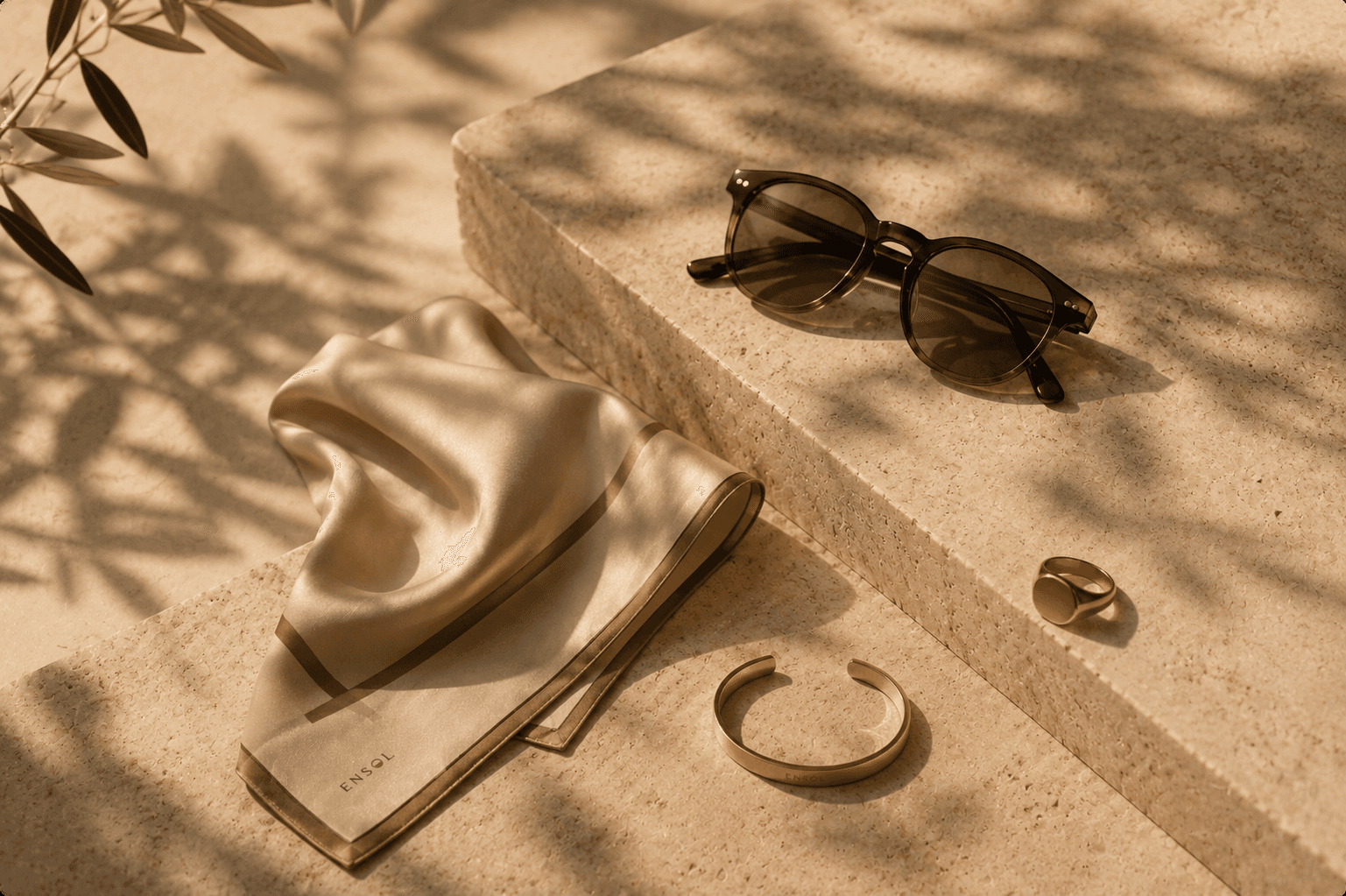 Silk scarf, sunglasses and gold jewellery on travertine stone